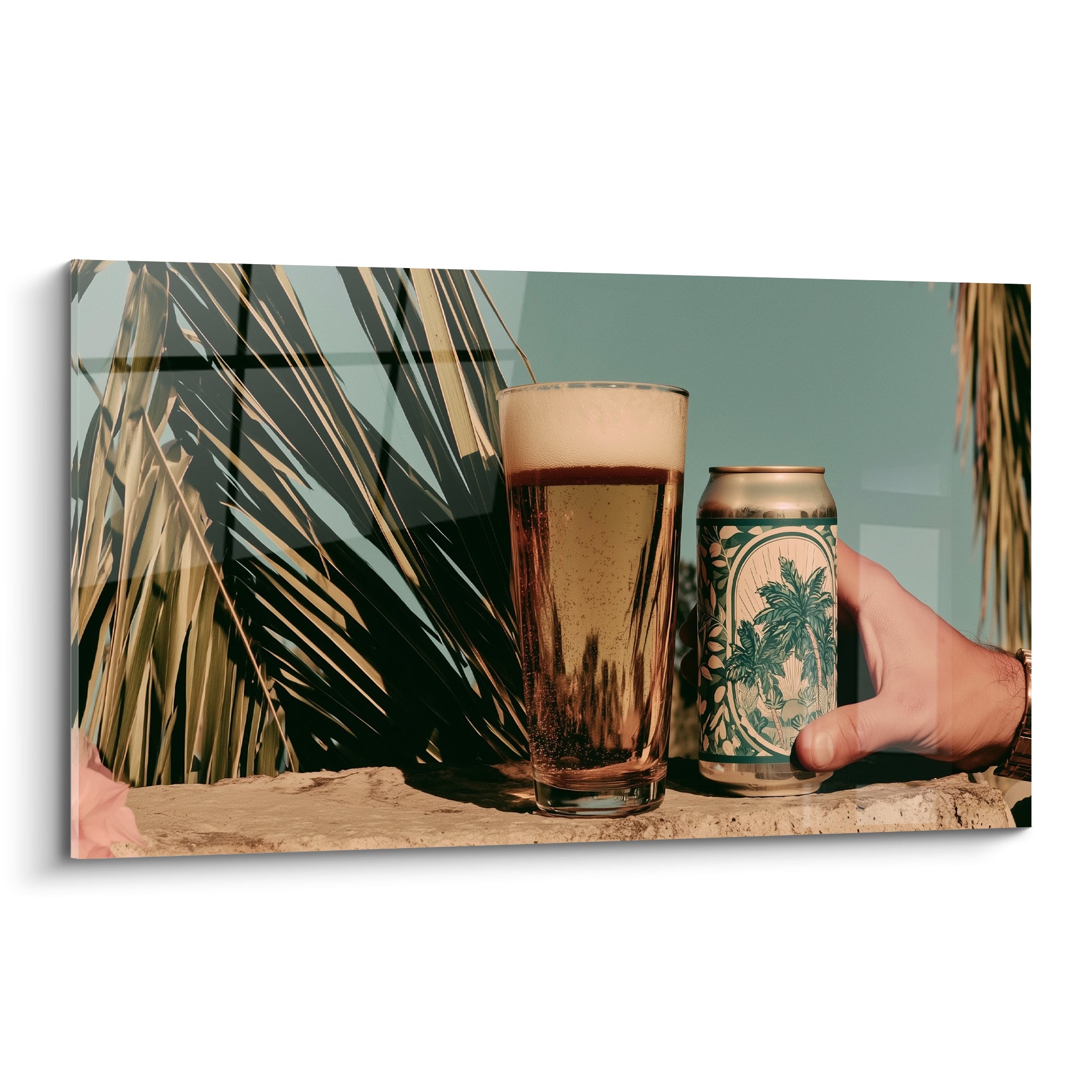 Verre de bière ambrée et canette aux palmes vertes devant un ciel bleu-vert intense