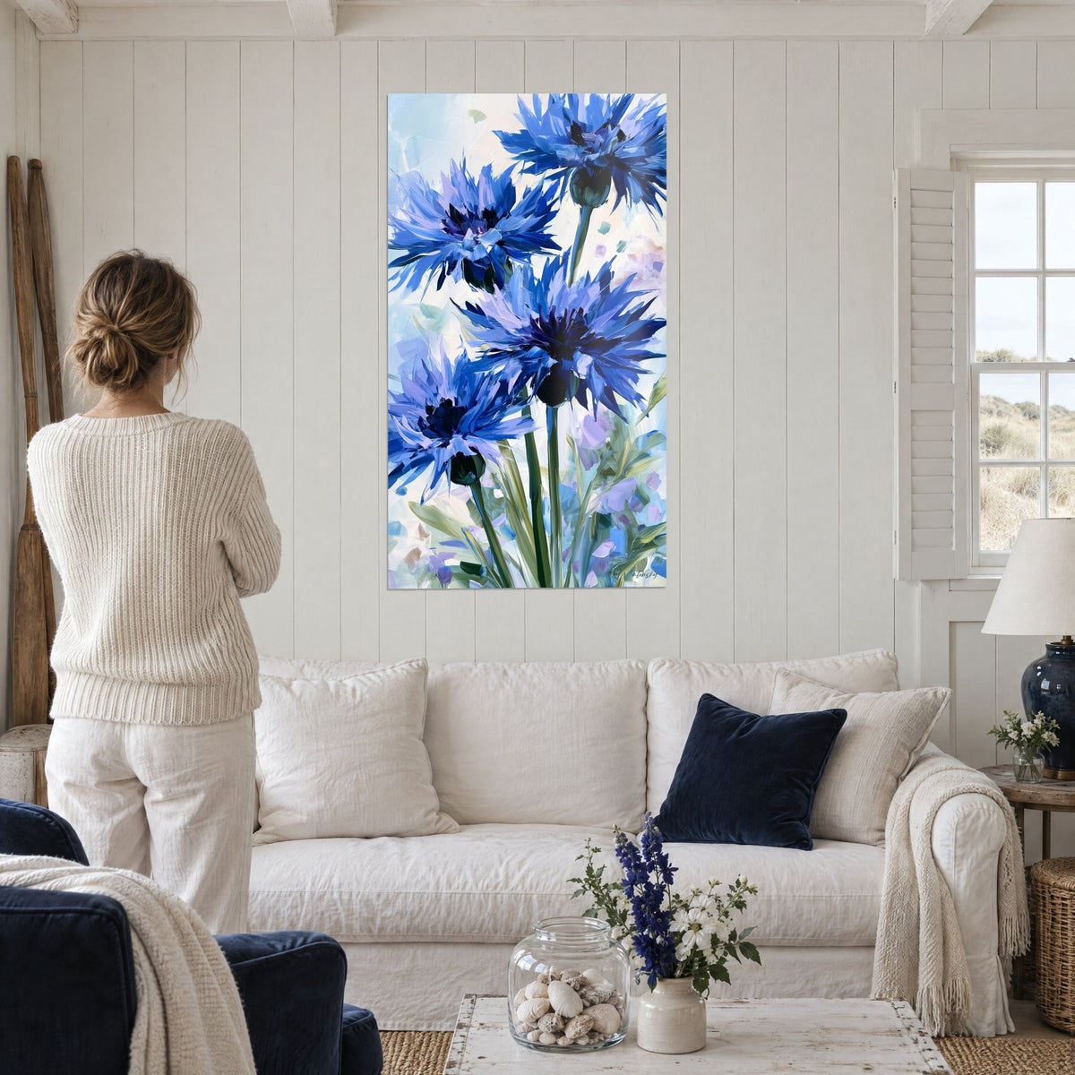 Schilderij korenbloemen met gescheurde blaadjes in kobaltblauw en lavendel, dikke penseelstreken, boven een bank in een lichte woonkamer