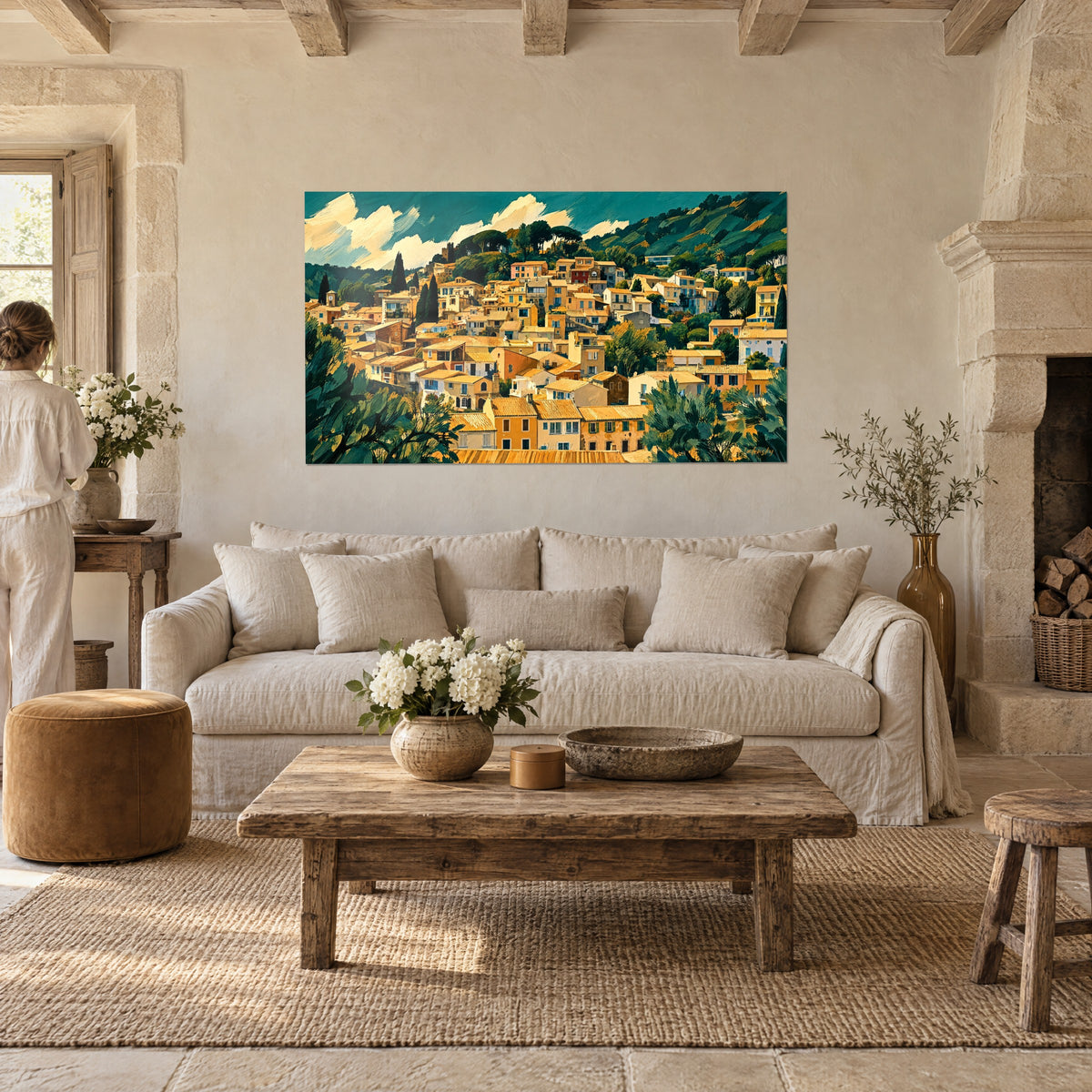 Tableau village provençal aux toits ocre dévalant une colline vert sapin, une personne de dos, au-dessus d'un canapé dans un salon lumineux