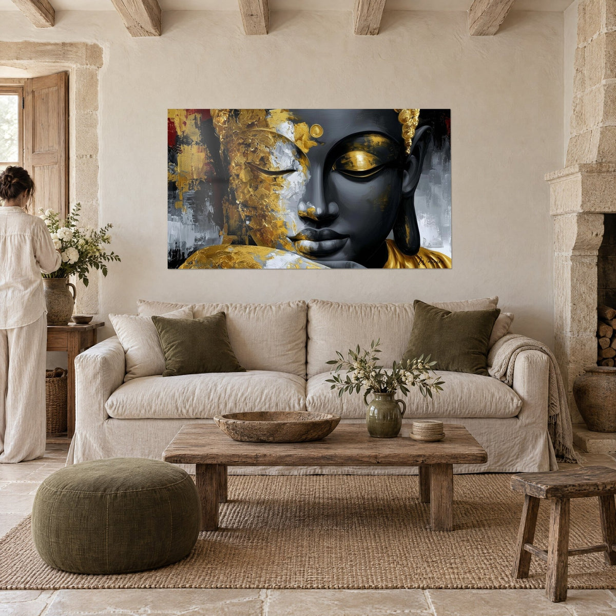 Tableau visage noir de Bouddha aux paupières dorées, éclats d'or et de gris, personne de dos, au-dessus d'un canapé dans un salon lumineux