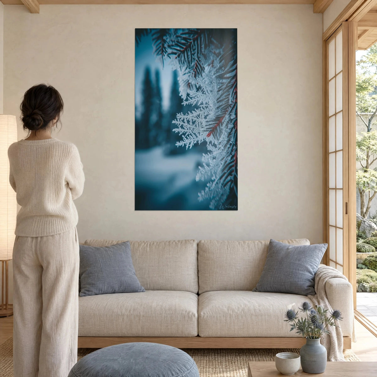 Tableau branche de sapin givrée, cristaux blancs et aiguilles bleu nuit vues de dos, au-dessus d'un canapé dans un salon lumineux