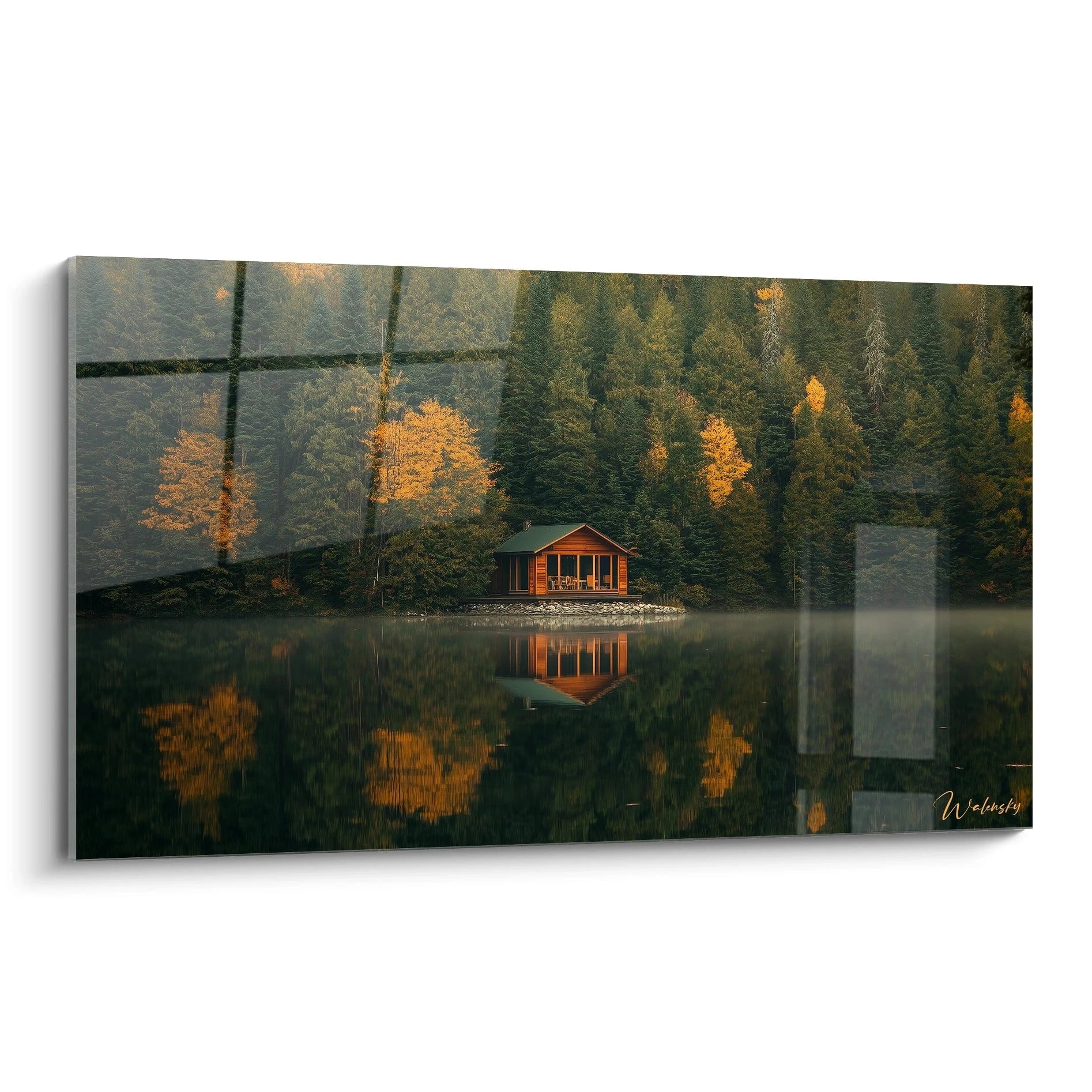 Un tableau paysage représentant un chalet en bois au bord d’un lac calme, entouré d’arbres verts et orange, avec un reflet symétrique sur l’eau et une brume légère en arrière-plan.