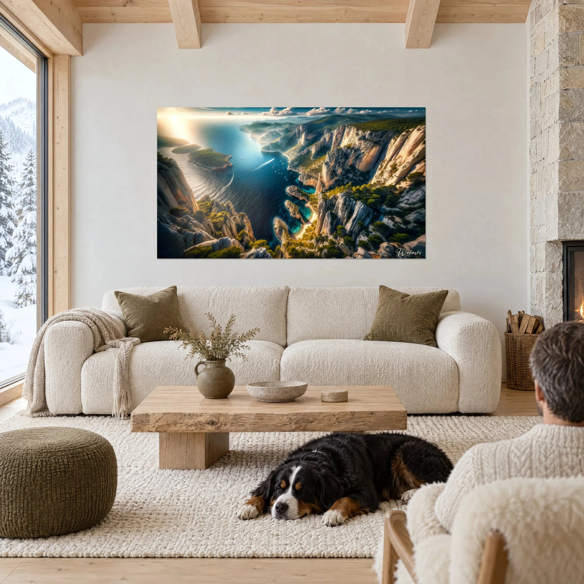Wall art aerial view of a cove, white cliffs and deep navy sea, dog lying down, above a sofa in a bright living room