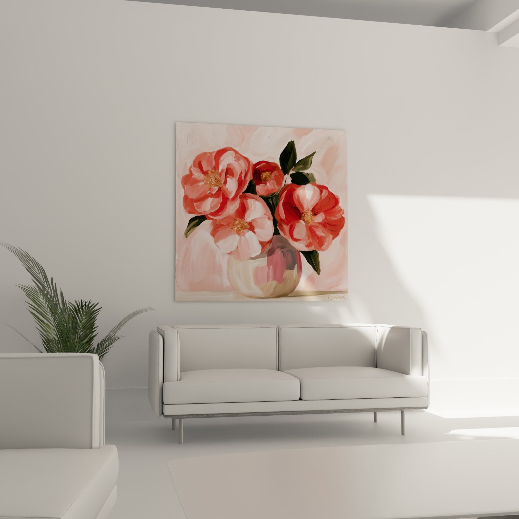 Fleurs de camélia roses et rouges au feuillage vert sombre, disposées au-dessus d'un canapé dans un salon lumineux.