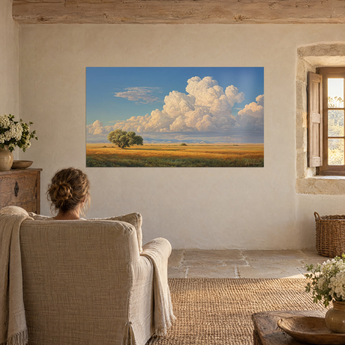 Tableau vaste ciel d'été, nuages crème gonflés, blés orangés et chêne vert à gauche, face à un fauteuil en lin près d'une fenêtre