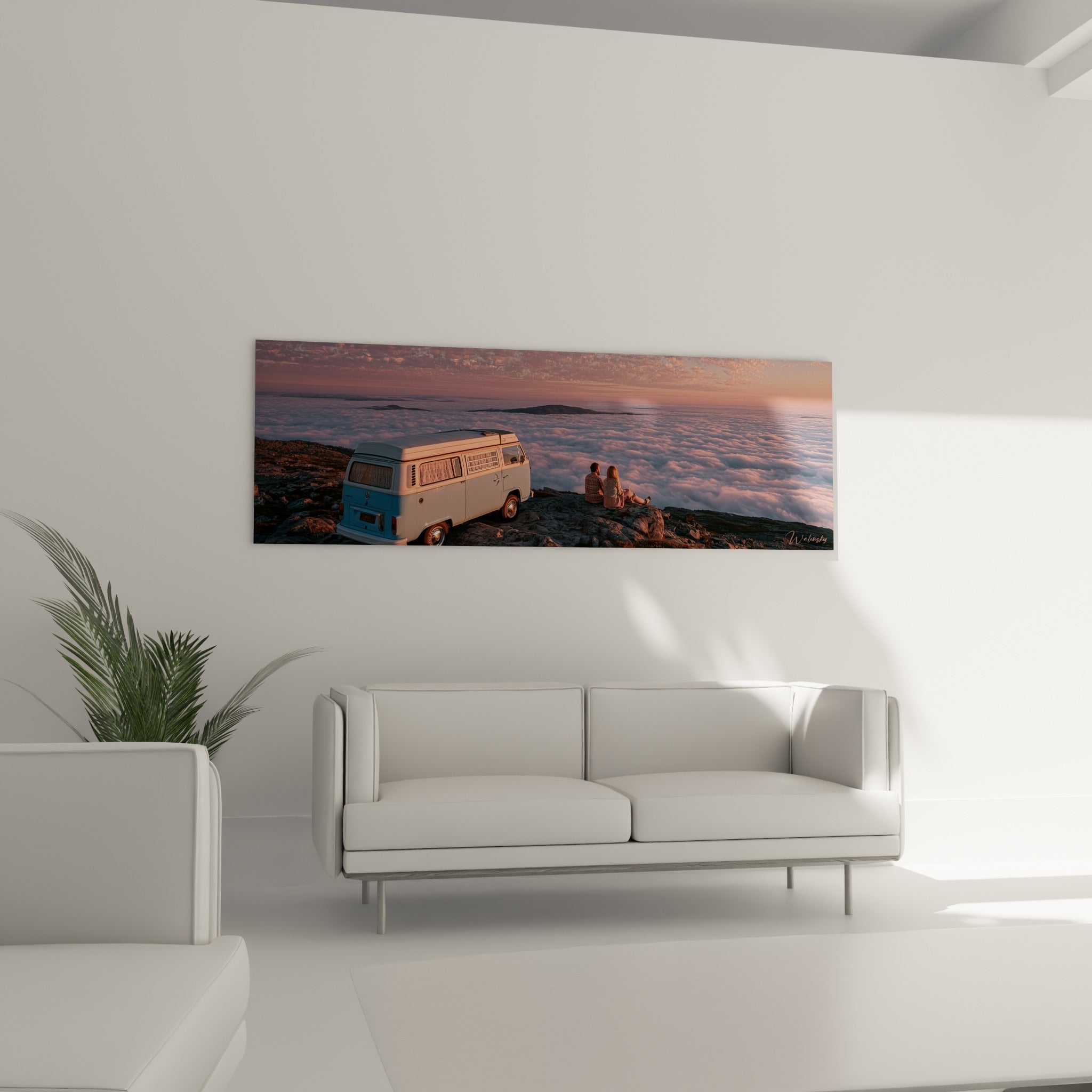 Silhouettes assises sur des rochers gris face au ciel rosé, au-dessus d'un canapé dans un salon lumineux