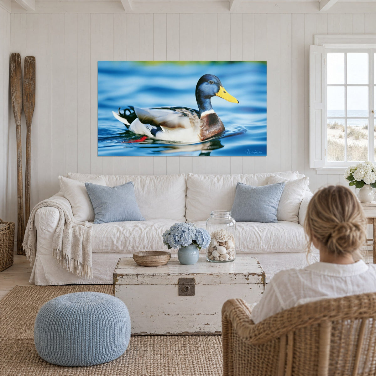 Tableau colvert tête bleu marine et bec jaune vif glissant sur l'eau azur, au-dessus d'un canapé dans un salon lumineux