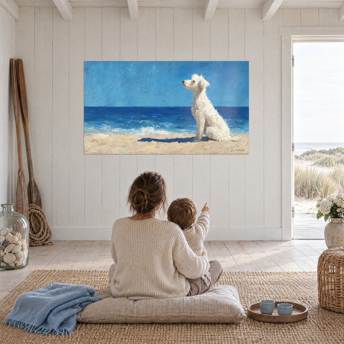 Quadro di un compagno dal pelo biondo riccio che fissa il mare blu, sabbia chiara, madre e figlio di spalle seduti su un cuscino