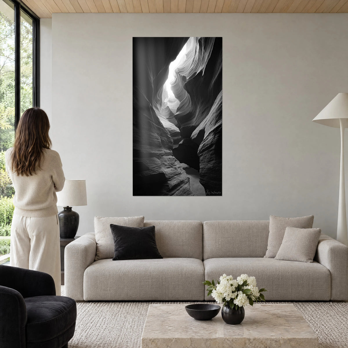 Tableau canyon de grès sculpté, parois grises ondulées et fente de lumière blanche, femme de dos, au-dessus d'un canapé dans un salon lumineux