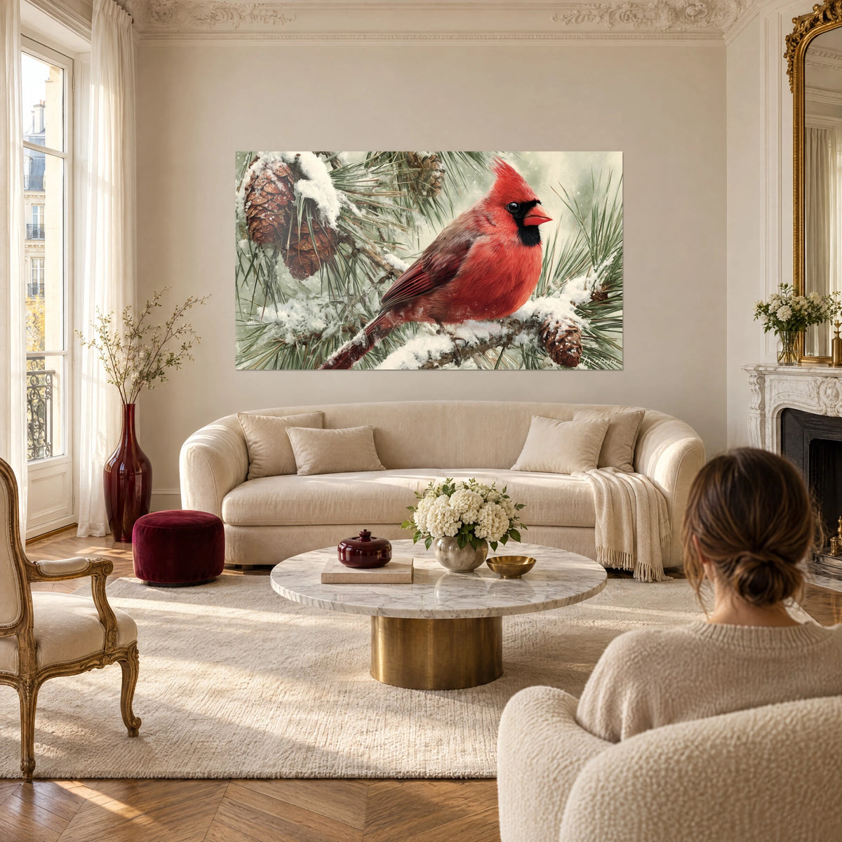 Wall art of a vivid red cardinal perched on a snowy pine branch, black mask, brown pine cones, above a sofa in a bright living room