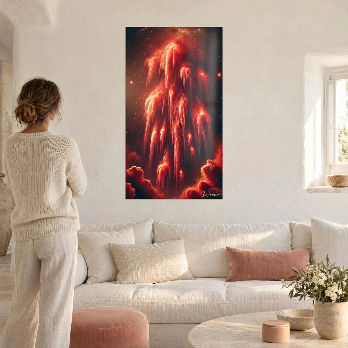 Quadro nebulosa scarlatta con filamenti fiammeggianti su fondo nero stellato, donna di spalle, sopra un divano in un soggiorno luminoso