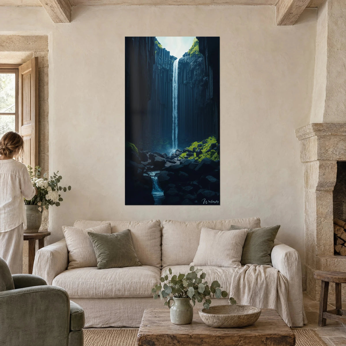 Tableau chute d'eau filiforme entre falaises de basalte noir, mousse vert acide, personne de dos, au-dessus d'un canapé dans un salon lumineux
