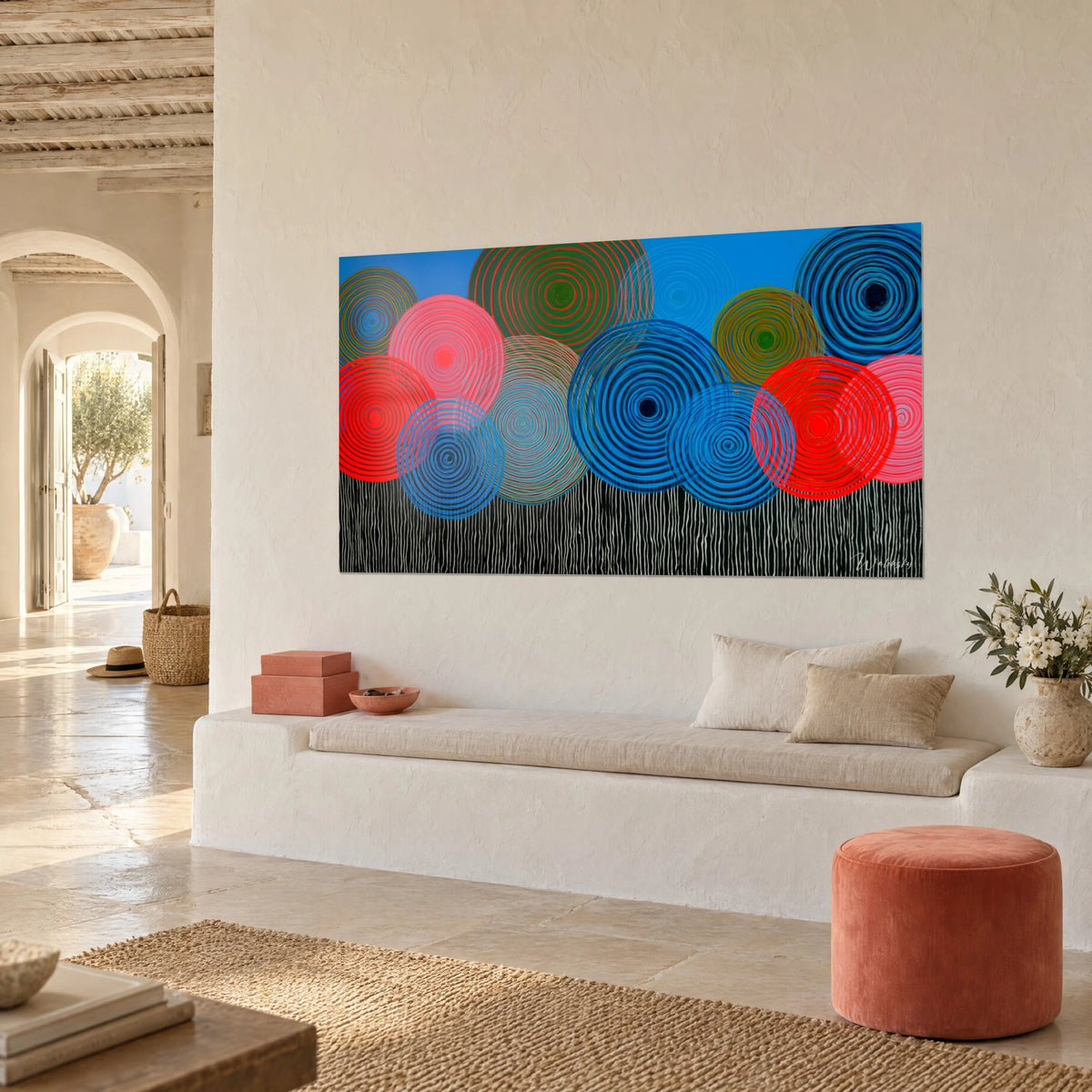 Cuadro con espirales hipnóticas rosas y turquesas sobre un cielo azur, colgado junto a un banco blanco de una casa mediterránea