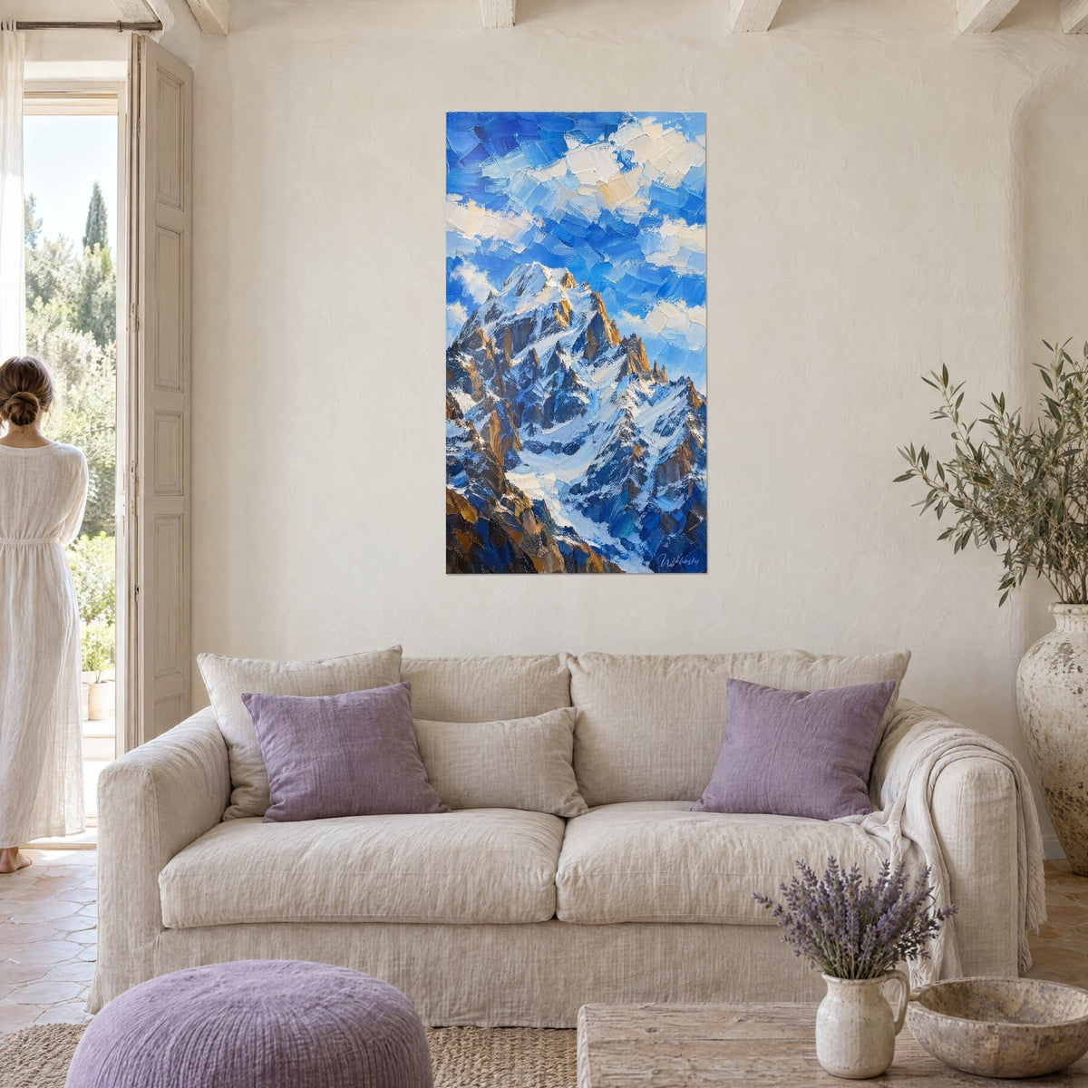 Cuadro de una enorme montaña nevada con agujas ocres bajo un cielo azul cobalto, textura gruesa con espátula, dos personas de espaldas, encima de un sofá en un salón luminoso