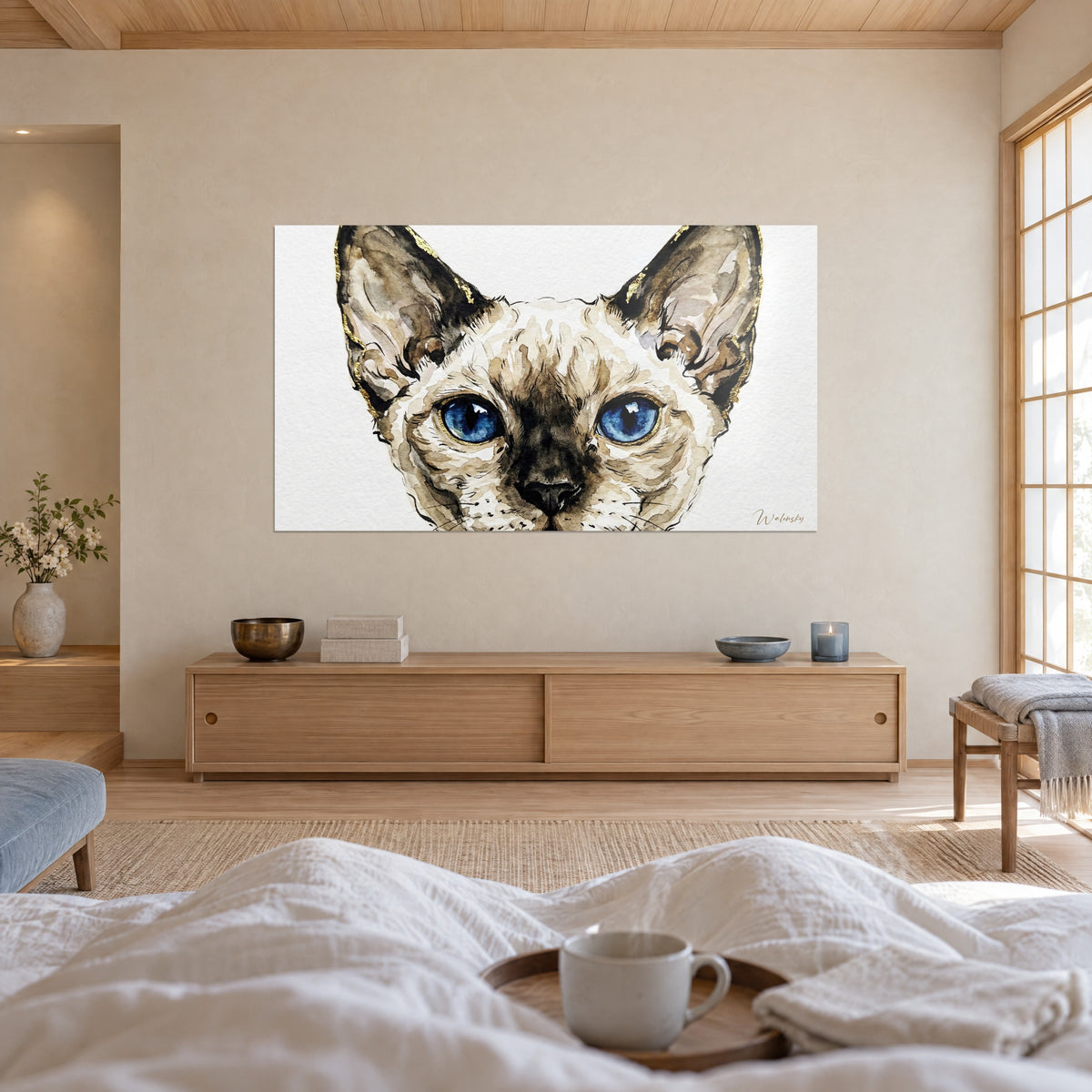 Quadro volto felino con muso crema e maschera marrone, pupille blu a fessura e linee dorate, con una persona di spalle, sopra un letto in una camera luminosa
