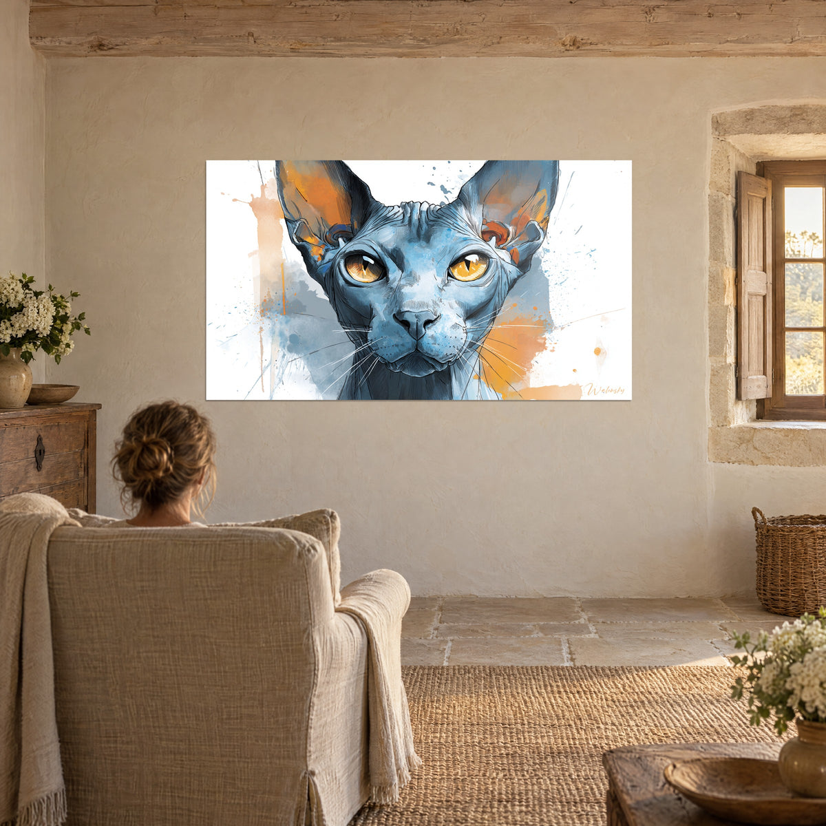 Cuadro rostro de esfinge de grandes ojos ámbar, fondo blanco salpicado de azul y naranja, frente a una mujer en un sillón