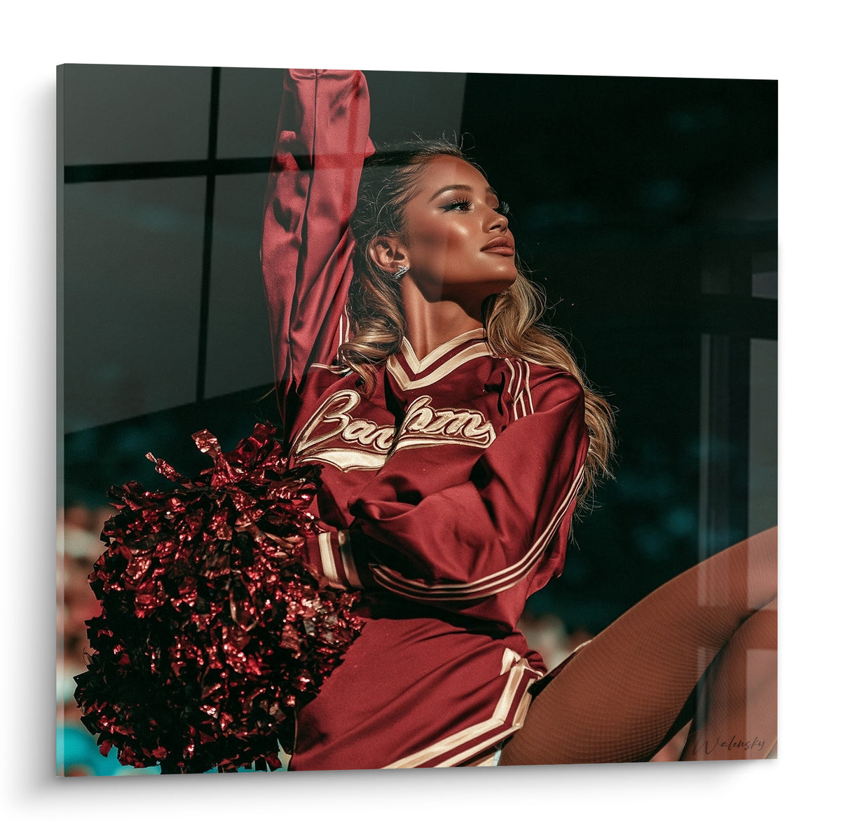 Pom-pom girl en uniforme bordeaux et blanc, bras levé, pompon rouge scintillant en gros plan