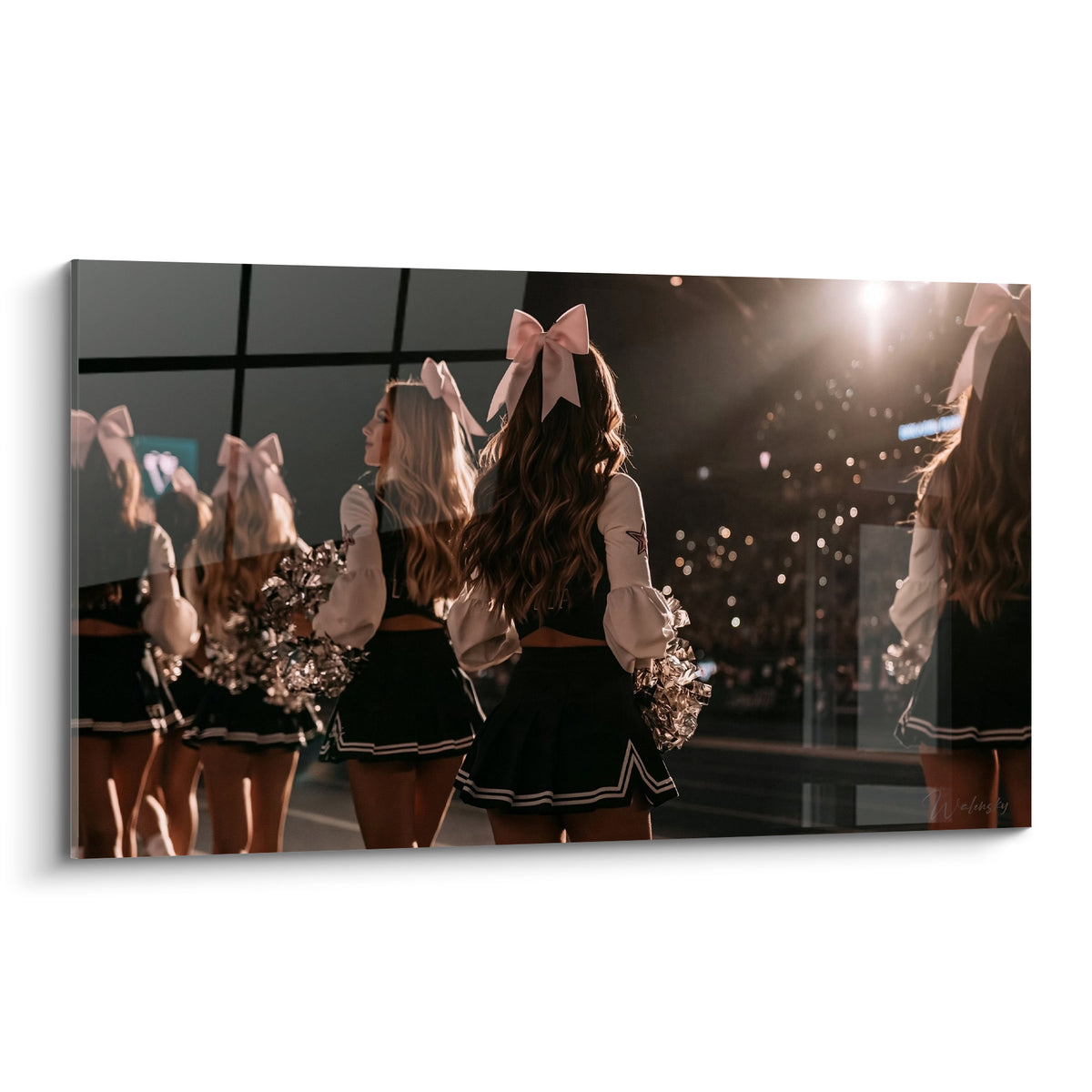 Pom-pom girls de dos aux nœuds roses, uniformes noirs et pompons argentés sous lumière dorée