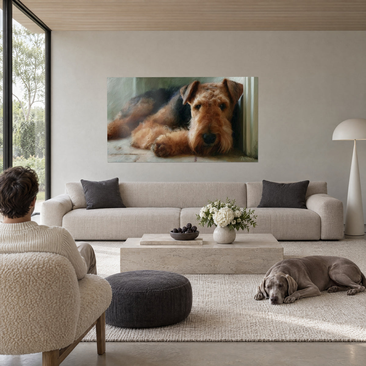 Cuadro perro terrier tumbado de pelo cobrizo y negro, hocico oscuro, persona de espaldas, encima de un sofá en un salón luminoso