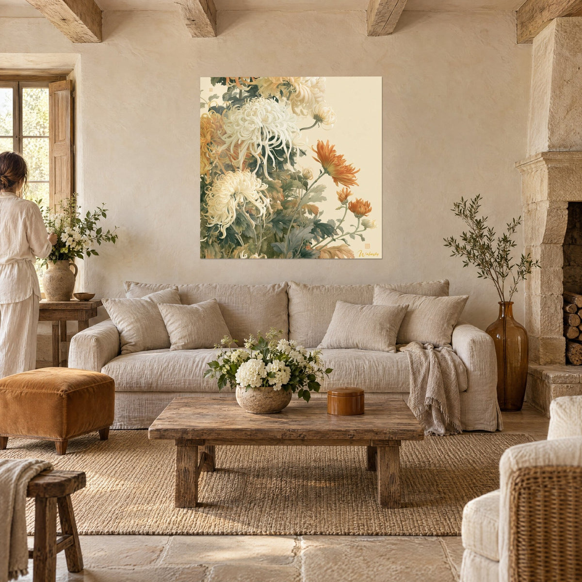 Tableau chrysanthèmes ivoire aux pétales filiformes et fleur orange, mur de pierre, deux personnes de dos au-dessus d'un canapé dans un salon lumineux