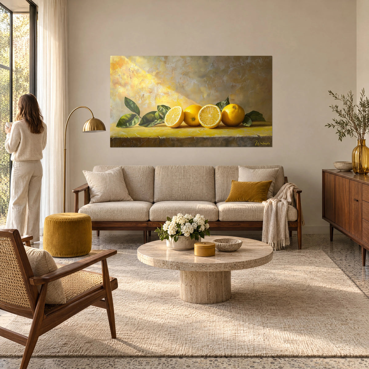 Quadro limoni succosi e foglie verdi su lastra gialla, sfondo ocra dorato, donna di spalle, sopra un divano in un soggiorno luminoso