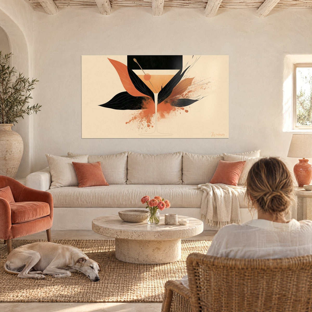 Tableau martini ocre et noir cerné de feuilles corail, regardé de dos, greyhound couché, au-dessus d'un canapé dans un salon lumineux