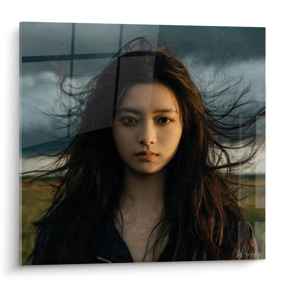 Visage aux cheveux bruns soulevés par le vent, ciel gris et lumière dorée, portrait intense