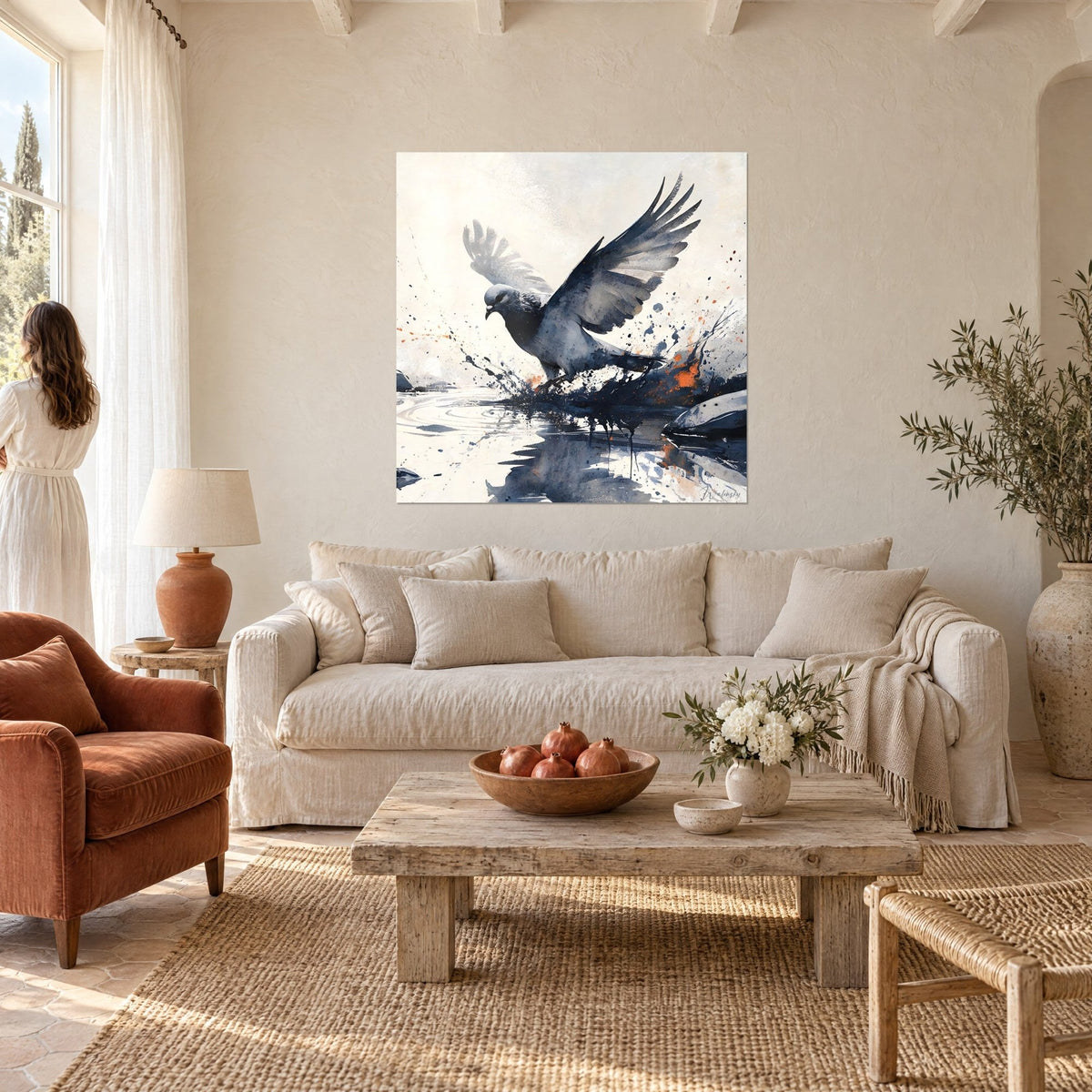 Tableau pigeon gris ardoise ailes levées, éclaboussures bleu nuit et orangées, femme de dos, au-dessus d'un canapé dans un salon lumineux