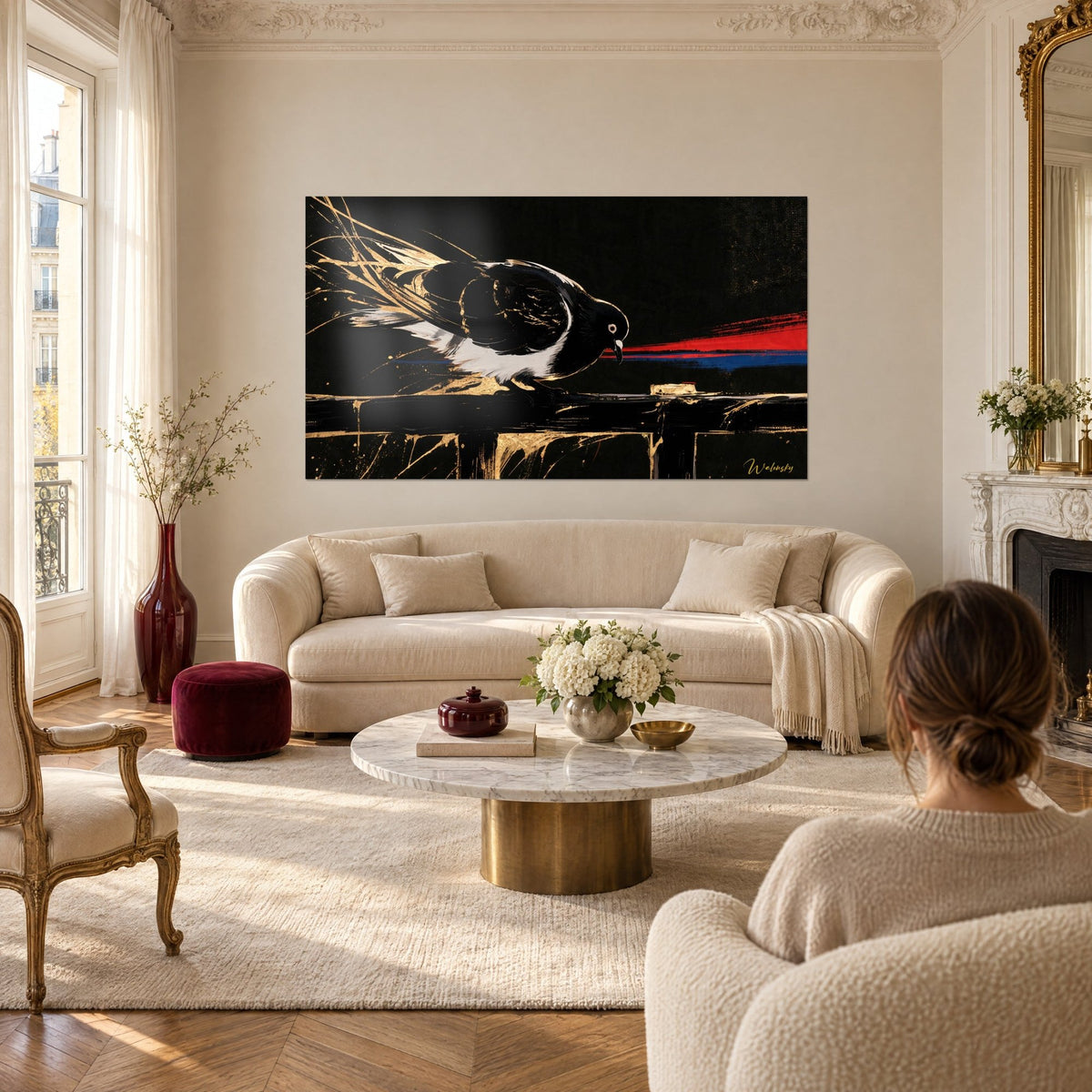 Quadro di un piccione nero dal ventre bianco, piume punteggiate d'oro e scia rossa su fondo scuro, sopra un divano in un soggiorno luminoso