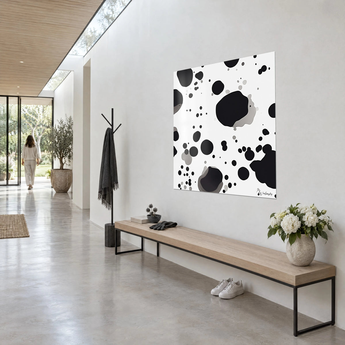 Tableau pois irréguliers noirs et gris pâle éclaboussés sur blanc, accroché en trois-quarts au-dessus d'un banc en bois clair