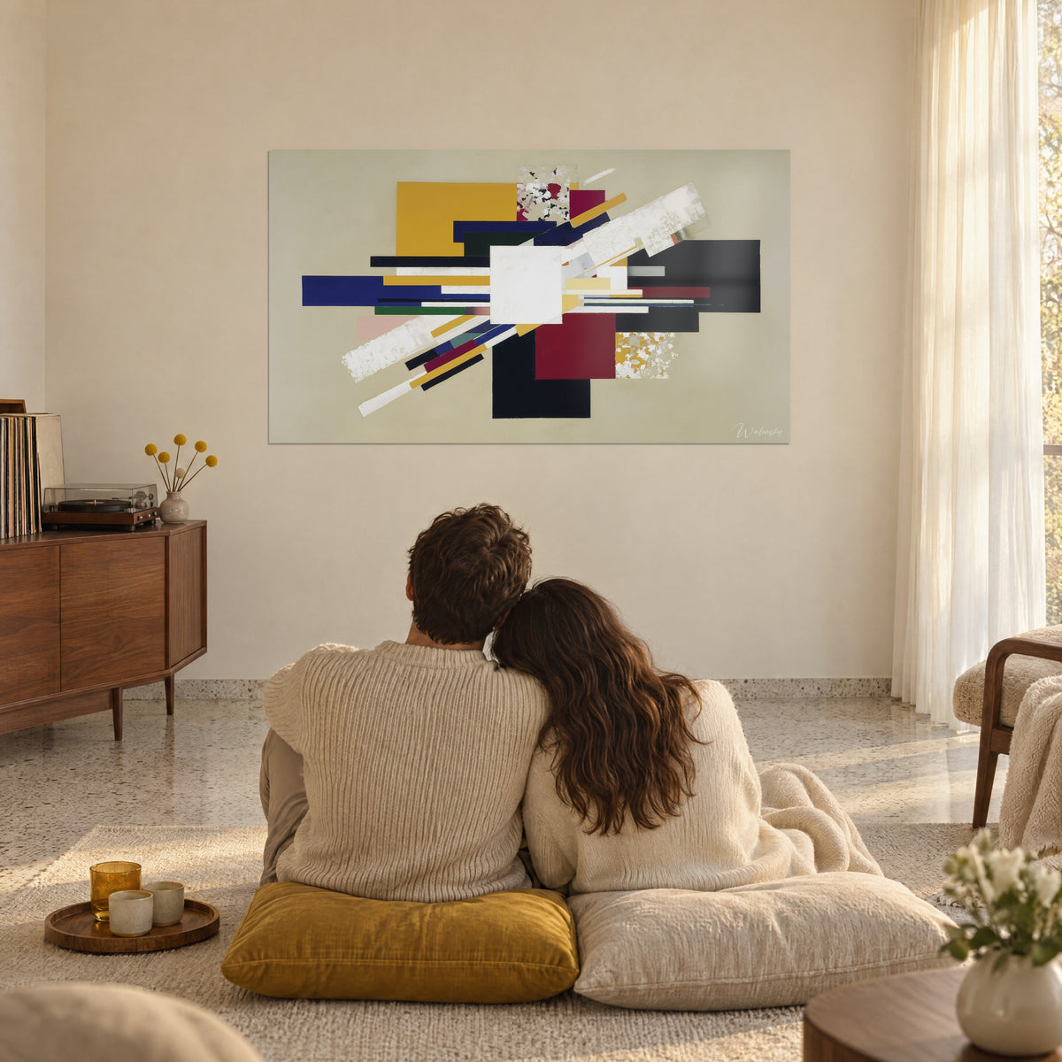 Cuadro geometría abstracta con bloques negros, burdeos y amarillo mostaza, trazos blancos oblicuos, encima de una pareja de espaldas sobre cojines