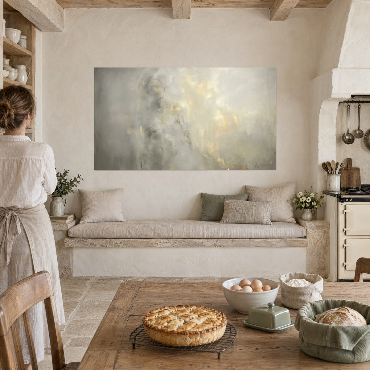 Tableau fantôme féminin flou aux touches d'or sur fond gris clair, accroché au-dessus d'une banquette en pierre, cuisine rustique