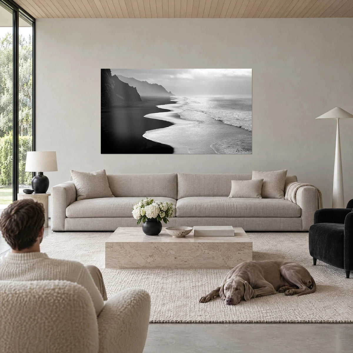 Tableau plage de sable noir bordée d'écume argentée, falaise sombre à gauche, ciel gris perle, au-dessus d'un canapé dans un salon lumineux