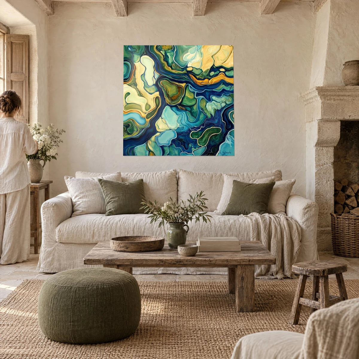Tableau rivières abstraites bleu marine et or, îlots verts en aplats, deux personnes de dos, au-dessus d'un canapé dans un salon lumineux