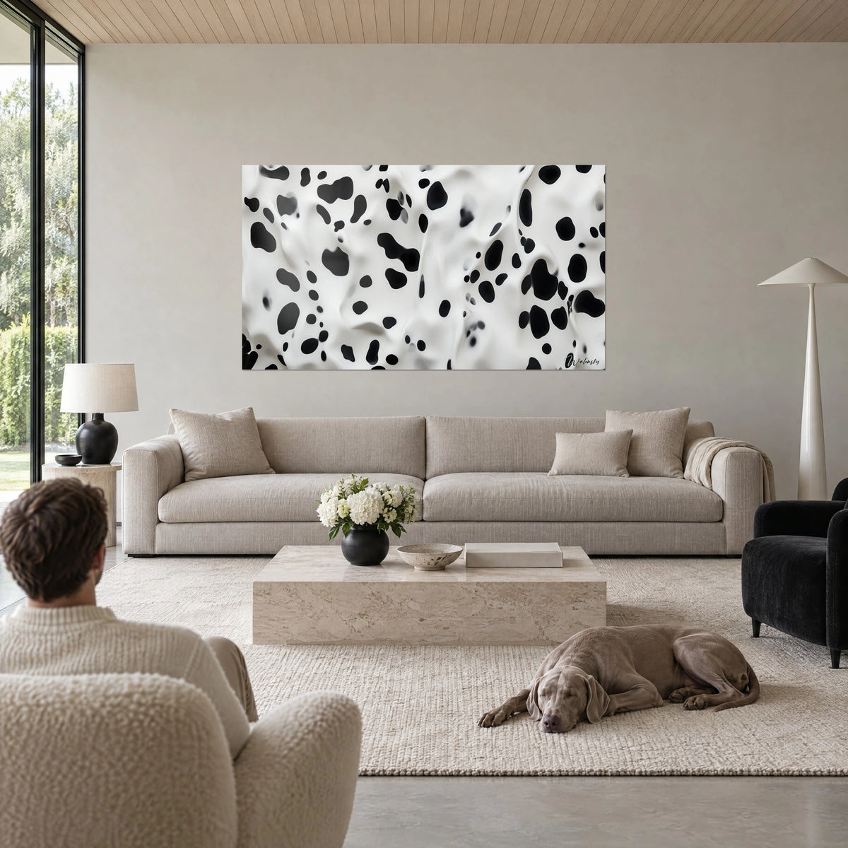 Tableau pelage dalmatien aux taches d'encre noire sur fond blanc crème, deux personnes de dos et un Weimaraner au-dessus d'un canapé dans un salon lumineux