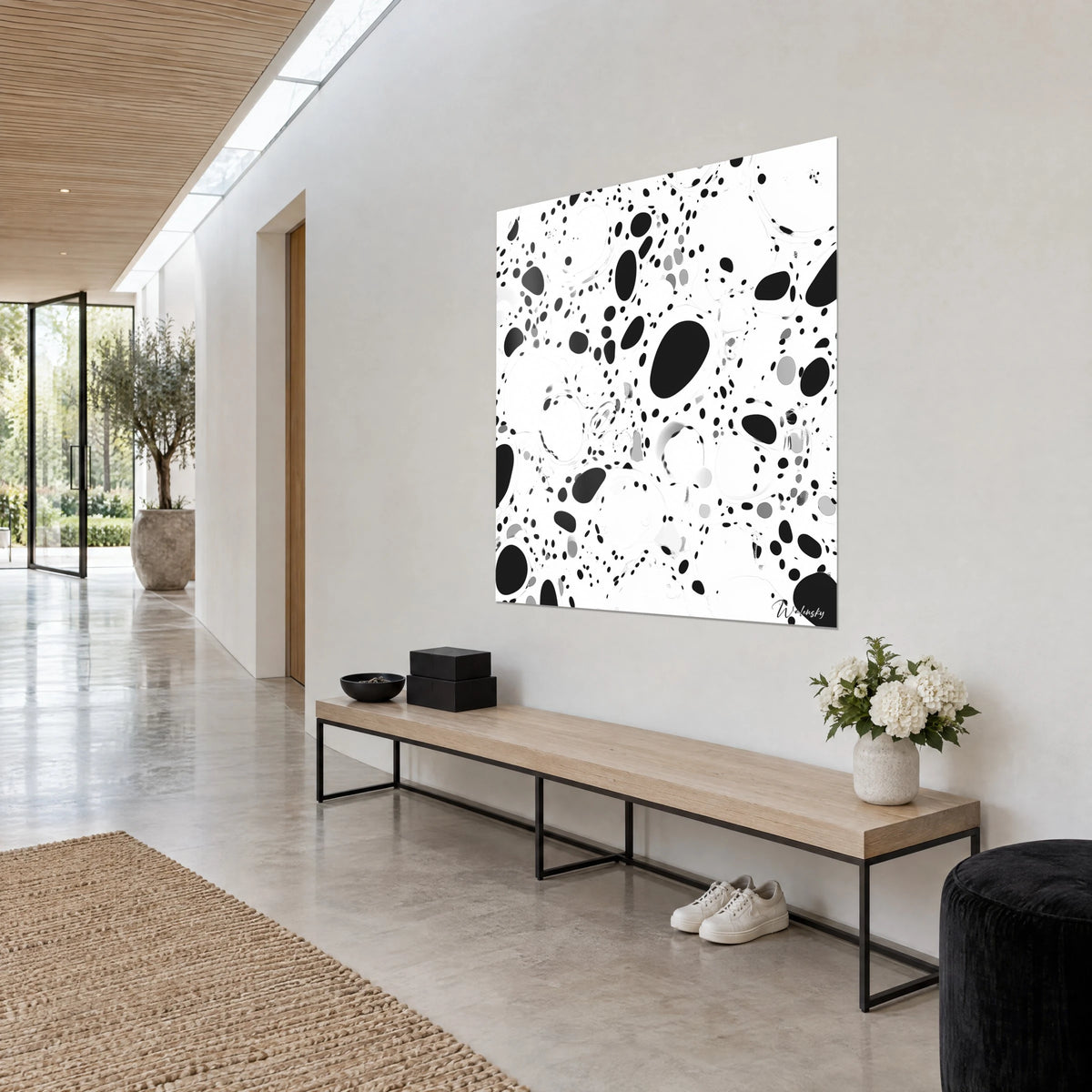 Quadro con motivo maculato in bianco e nero, grosse gocce d'inchiostro e pois sottili, appeso sopra una panca di legno in un corridoio