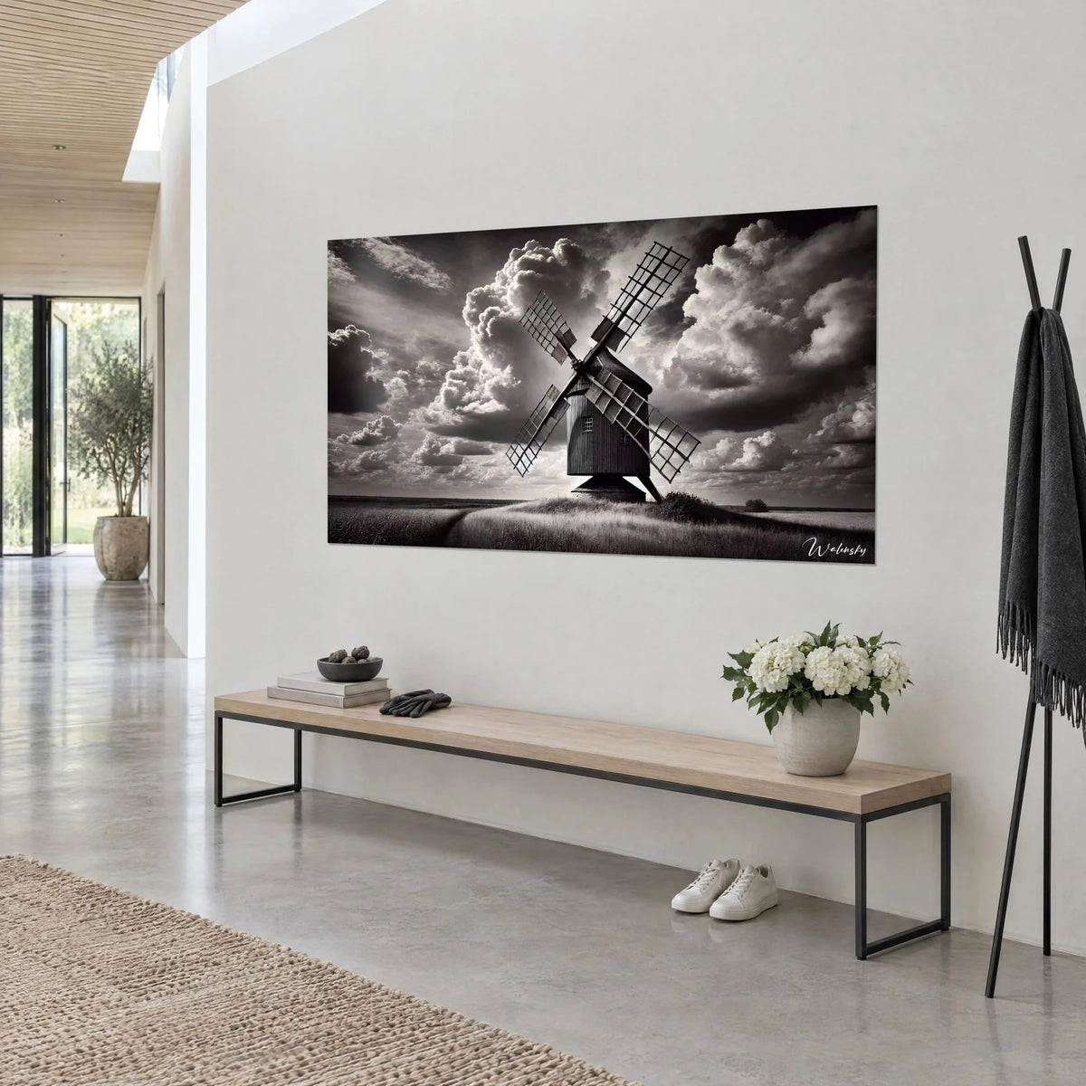 Quadro di un vecchio mulino in legno scuro, pale incrociate e nuvole bianche gonfie su sfondo antracite, sopra una panca da salotto