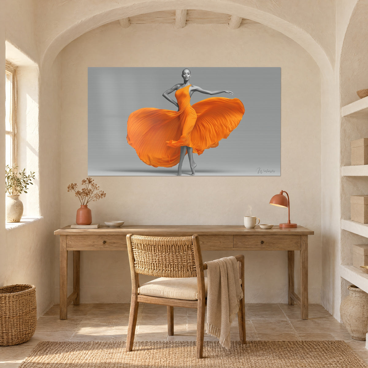 Cuadro bailarina desnuda abstracta envuelta en un vestido naranja en forma de abanico sobre fondo gris, encima de un escritorio de madera clara y una lámpara terracota