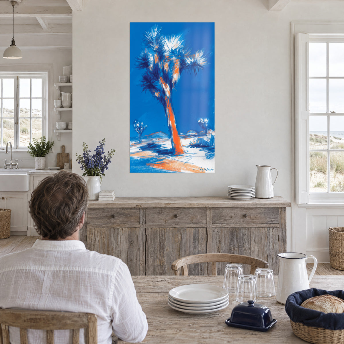 Wall art Joshua Tree palm in chalk strokes, orange trunk and blue sky, man seen from behind at a table, seaside house