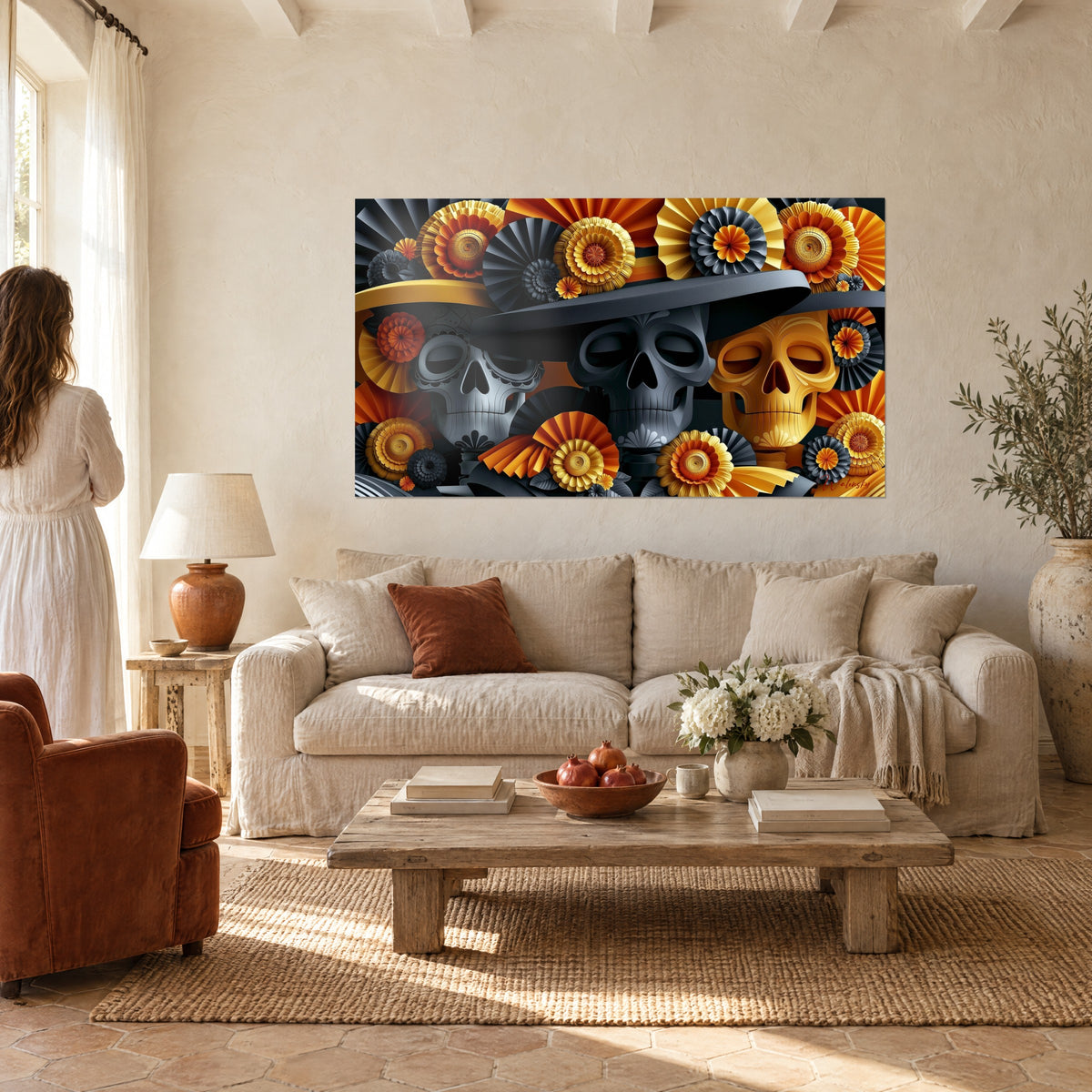 Gemälde drei Totenschädel unter schwarzem Sombrero, Rosetten aus orangefarbenem und gelbem Papier, Frau von hinten, über einem Sofa in einem hellen Wohnzimmer
