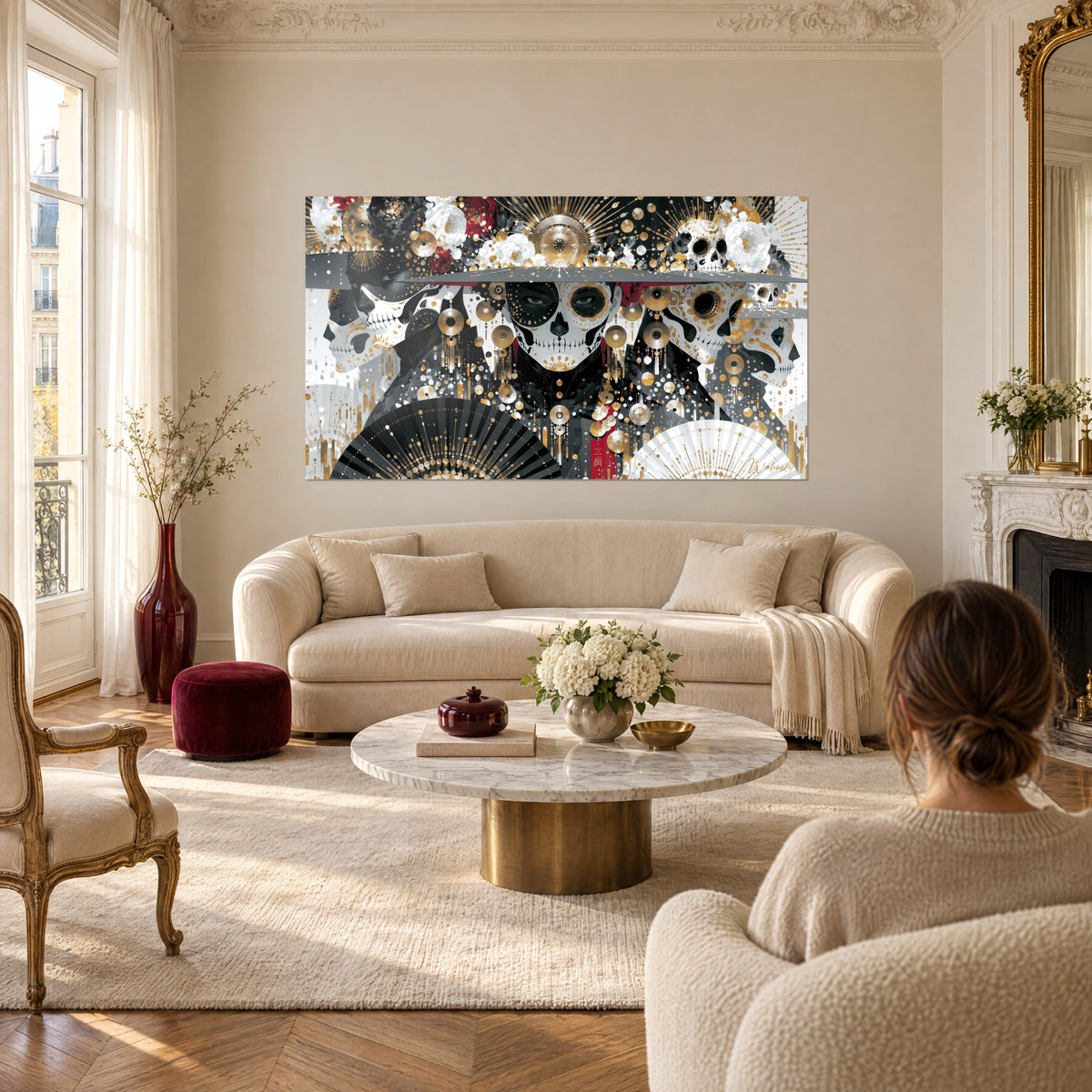 Tableau crâne en sucre peint noir et blanc, médaillons dorés et éventails déployés, au-dessus d'un canapé dans un salon lumineux