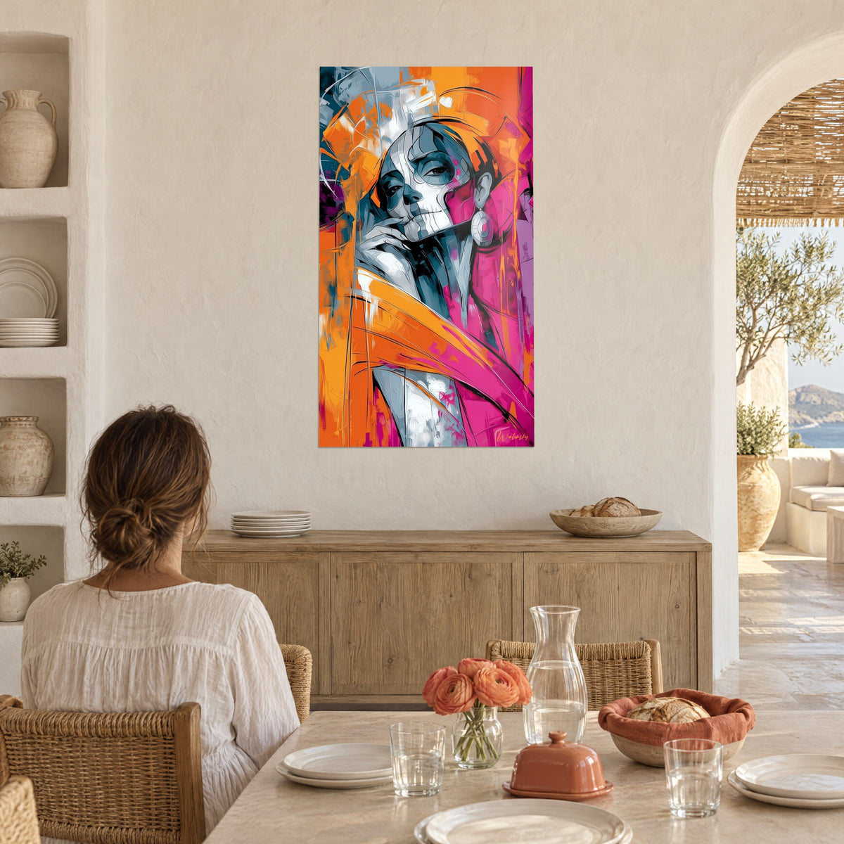 Wall art of a woman with a painted skeleton face in burnt orange and fuchsia tones, facing a dining table decorated with salmon carnations, arched white wall