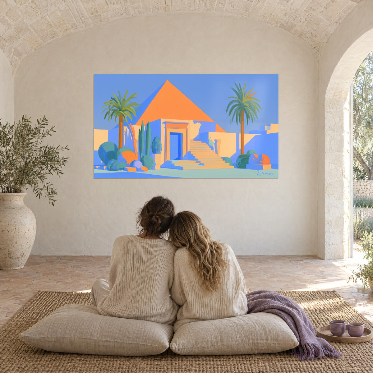 Wall art serene Egyptian desert, orange pyramid, blue facade and slender palm trees, couple seen from behind embracing on cream cushions