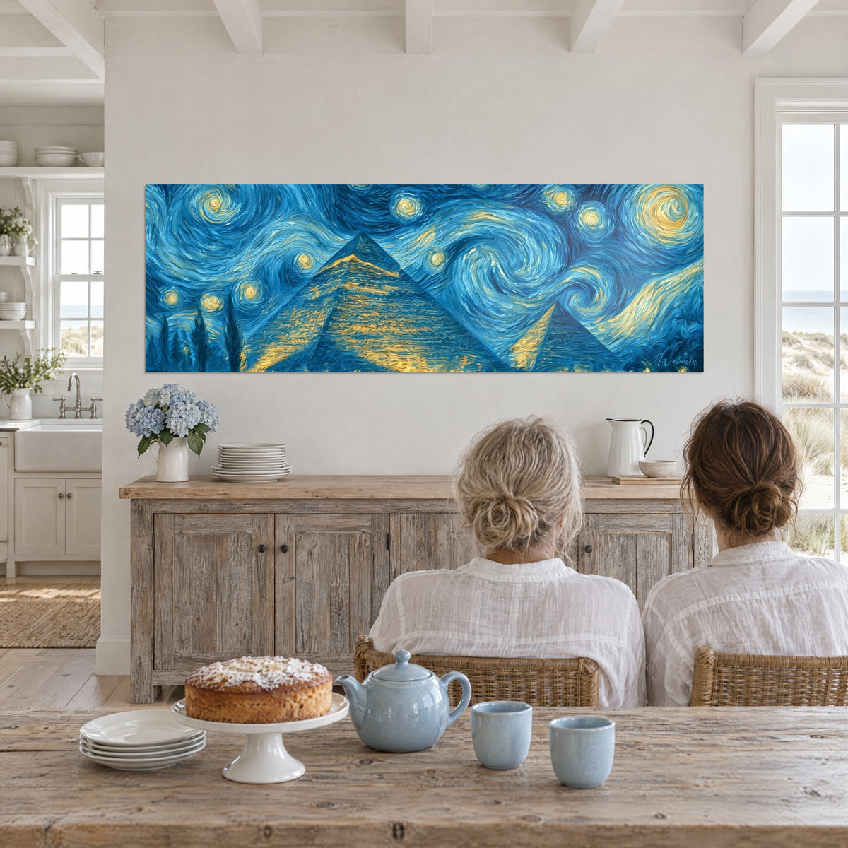 Cuadro monumentos egipcios bajo un firmamento azul y dorado, dos mujeres de espaldas sentadas a una mesa, aparador claro y tarta, casa de playa