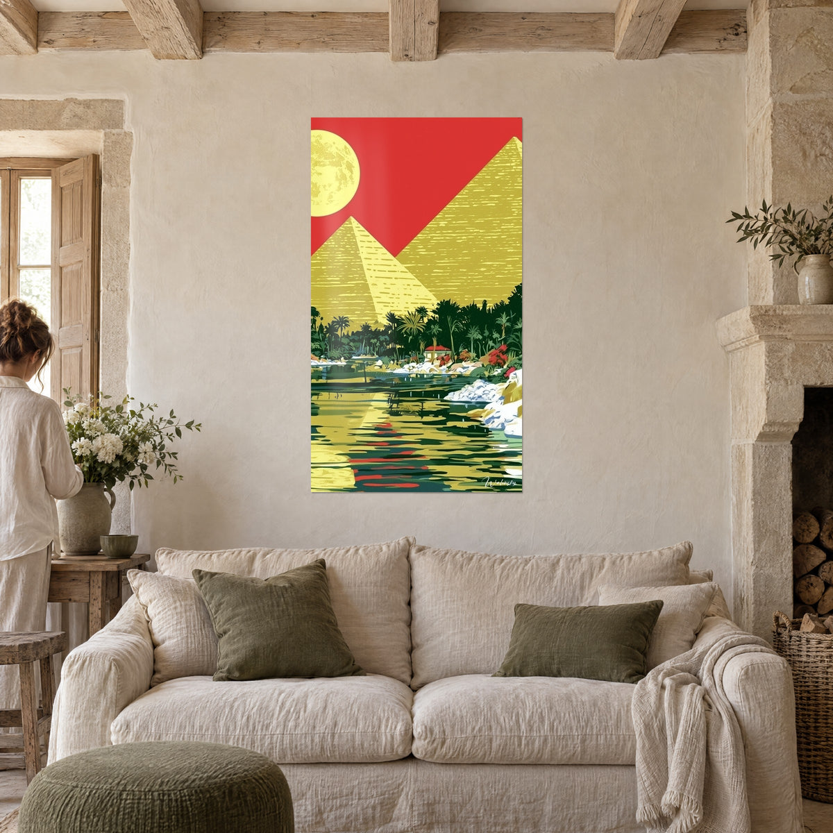 Quadro piramidi in toni ocra sotto un cielo rosso, luna gialla e palmeto verde, persona di spalle, sopra un divano in un soggiorno luminoso