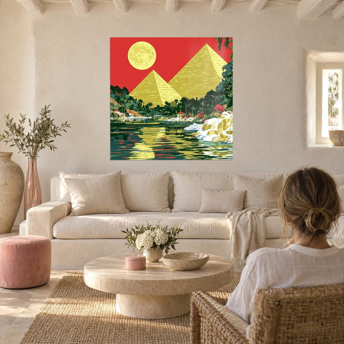 Schilderij met goudgele piramides onder een felrode hemel en volle maan, palmenoase, boven een bank in een lichte woonkamer