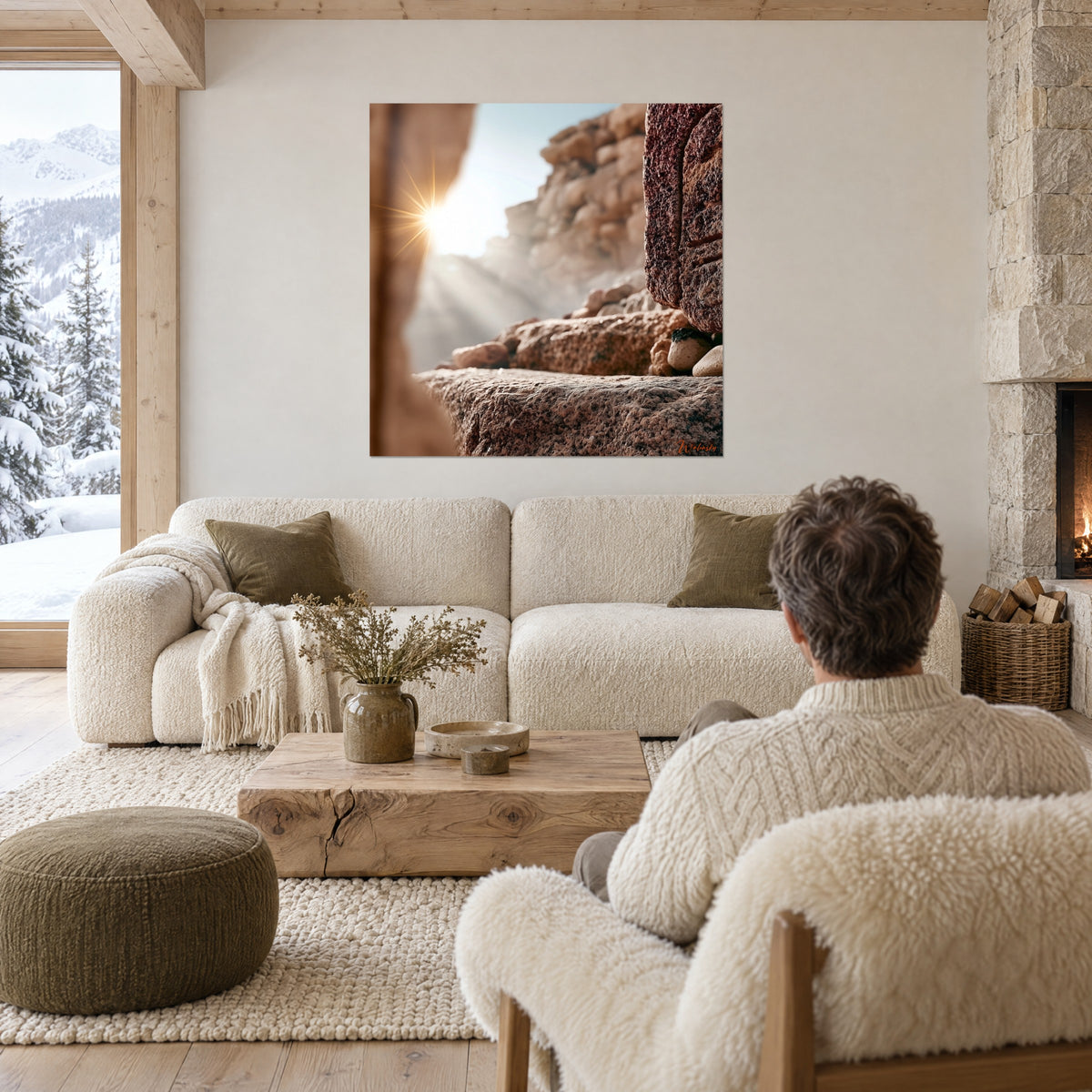 Gemälde einer felsigen Höhle in Ocker und Braun, ein sternförmiges Sonnenlicht bricht links hindurch, Mann von hinten, über einem Sofa in einem hellen Wohnzimmer