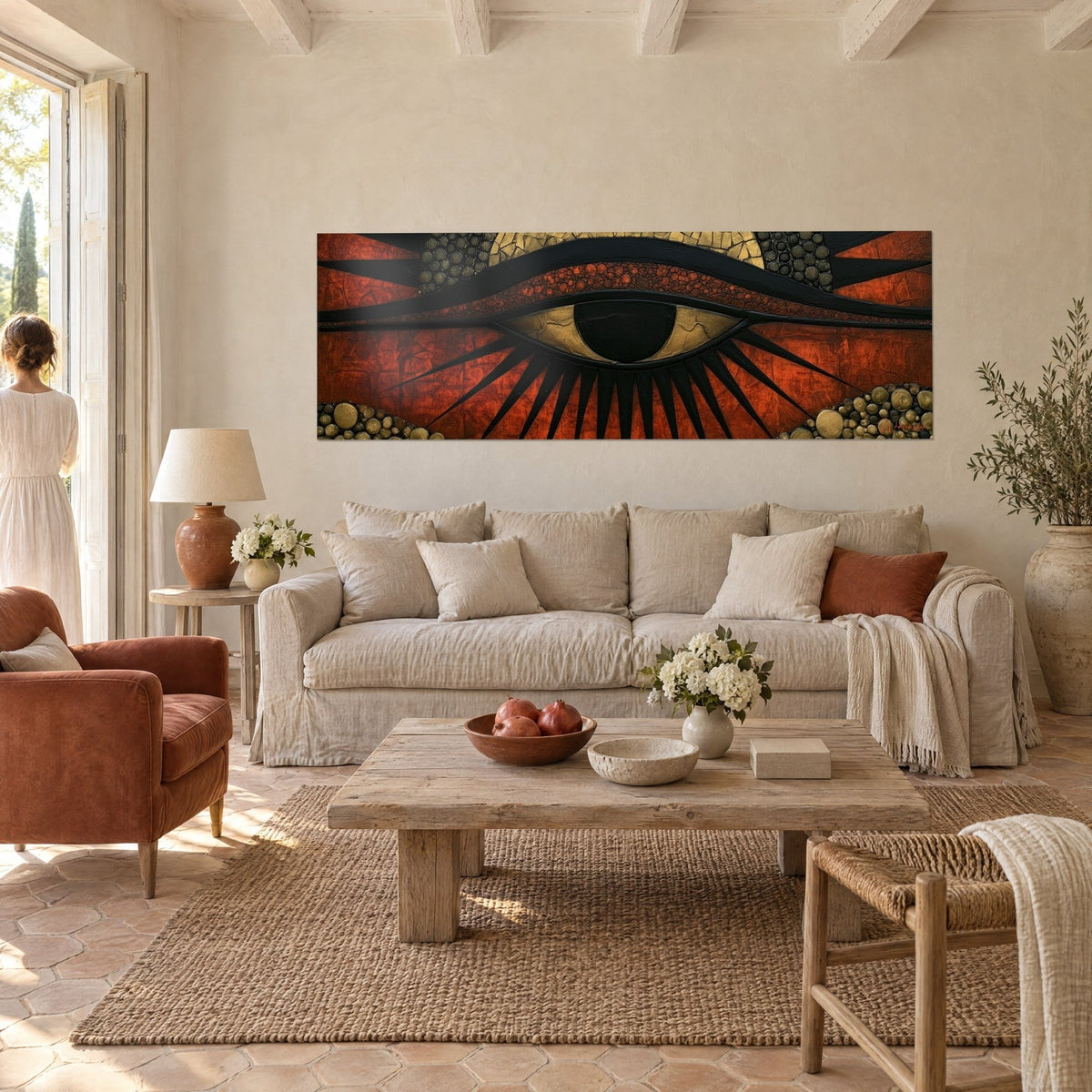 Cuadro ojo de Horus con contorno negro, iris oscura y pestañas en rayos sobre fondo rojo ladrillo, encima de un sofá en un salón luminoso