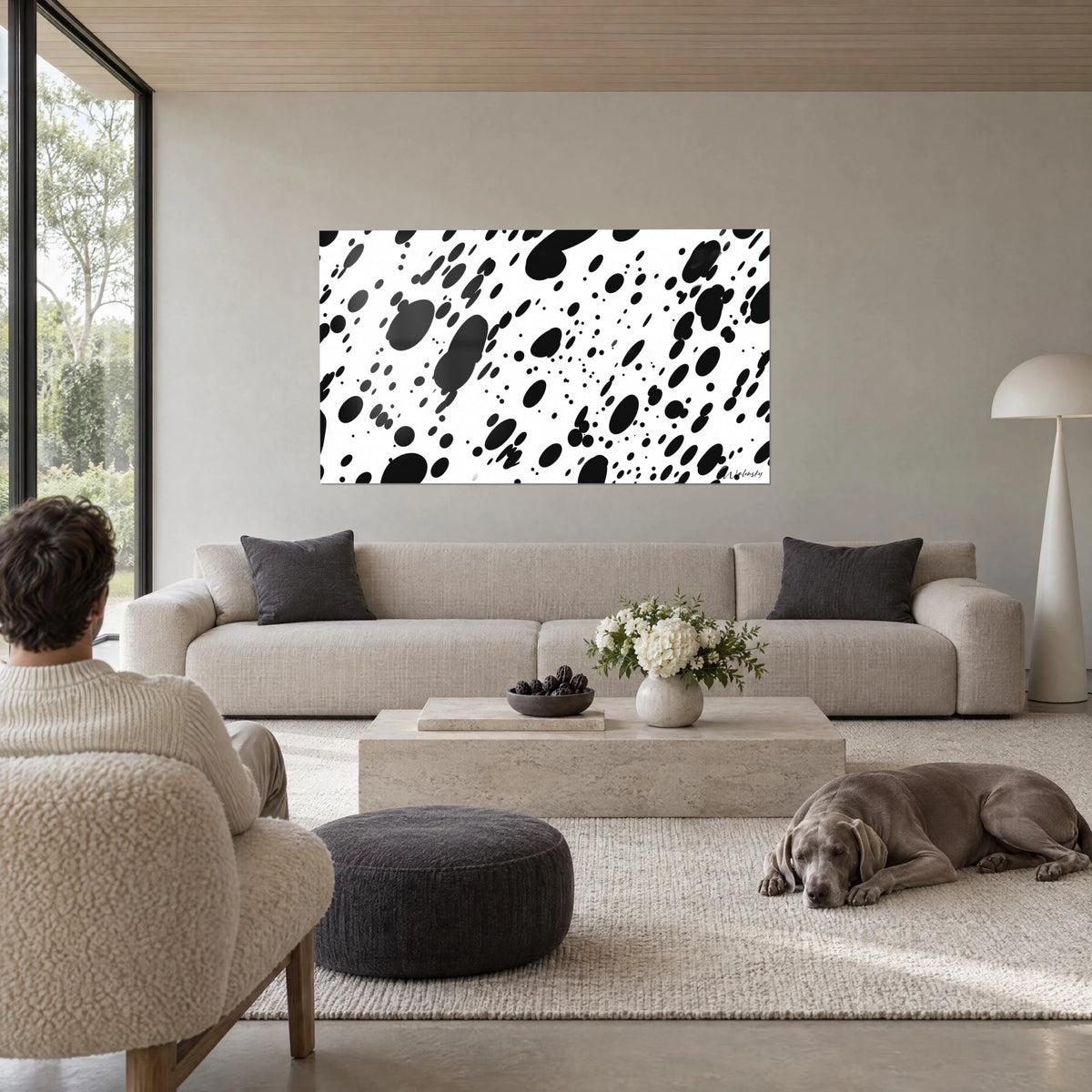Tableau taches d'encre noires sur fond blanc pur, gouttes semées en diagonale, au-dessus d'un canapé dans un salon lumineux