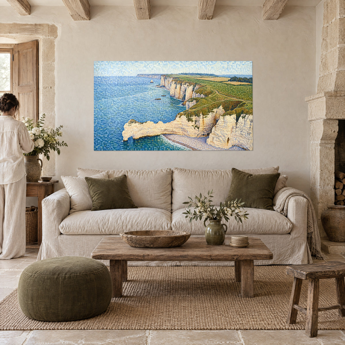 Schilderij krijtrotsen van Étretat in pointillisme, crèmekleurige rotsboog boven blauwe zee en groene weide, boven een bank in een lichte woonkamer